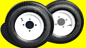 Two black tires with white rims on a dark background